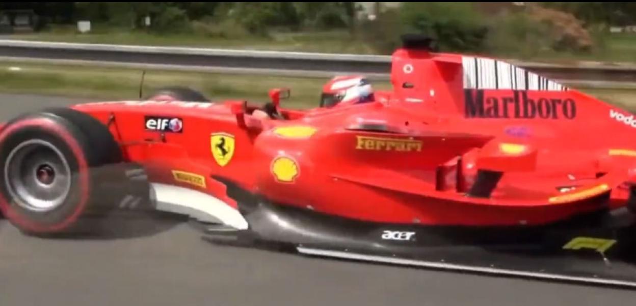 A red Formula 1 car driving on a motorway.