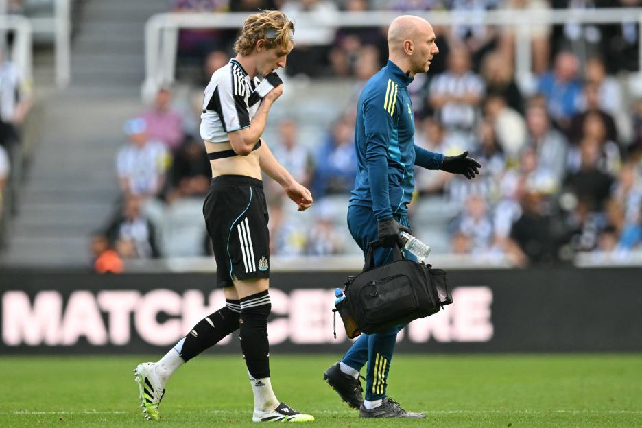 Injured soccer player Anthony Gordon leaves the field assisted by a medical professional.