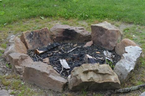 Stone fire pit with ashes and wood.