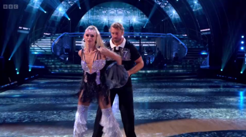 A male and female dancer performing on a brightly lit stage.