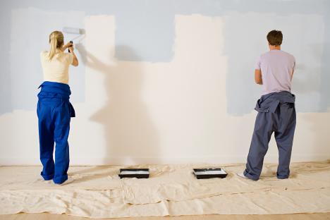 A couple painting a wall.