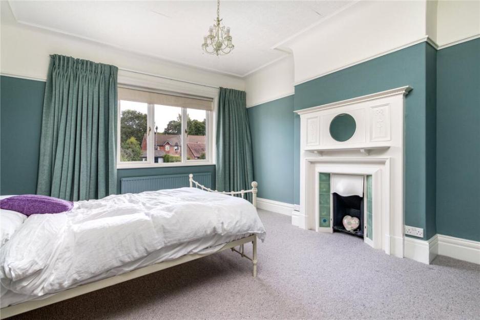 Bedroom with white bed, white fireplace, and teal walls.