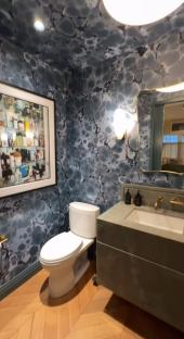 Graham Norton's New York townhouse bathroom with patterned wallpaper, toilet, sink, and herringbone flooring.