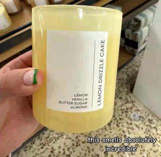 A hand holding a lemon drizzle cake candle from Tesco.
