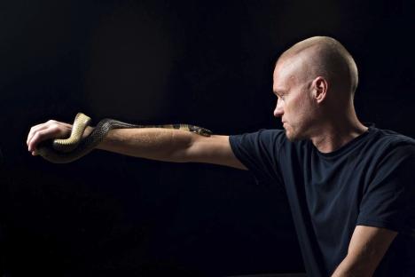 Man with hyper-immunity to snake venom holding a water cobra.