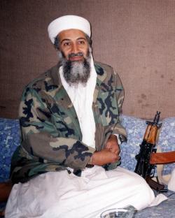 Osama bin Laden sitting with an AK-47.