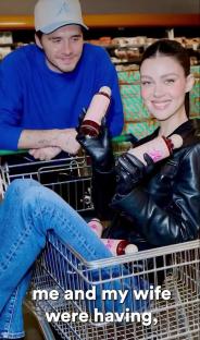 Brooklyn Beckham and his wife in a shopping cart, holding bottles of hot sauce.