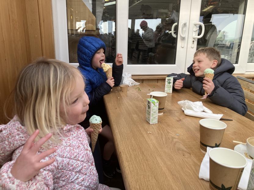 Three children eating ice cream at a table.