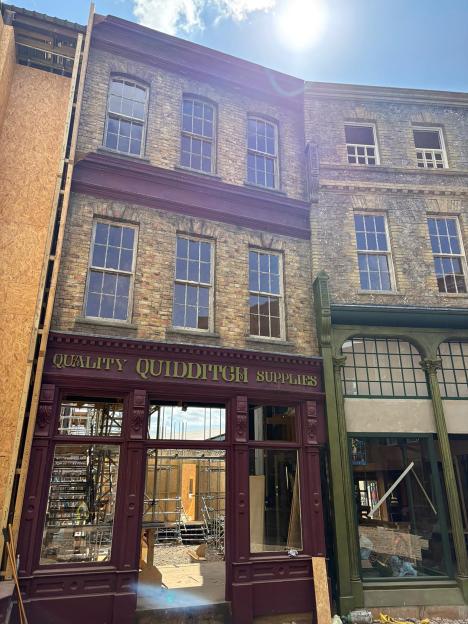 Diagon Alley set under construction, with a visible "Quality Quidditch Supplies" sign on a maroon storefront.