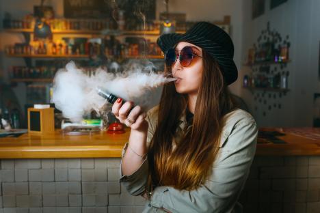 Young woman vaping in a vape shop.