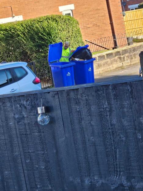 Aidan Edwards, wearing a neon vest, empties two blue bins outside Chelsea Jones's home.