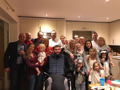 Large group photo of family and friends in a kitchen.