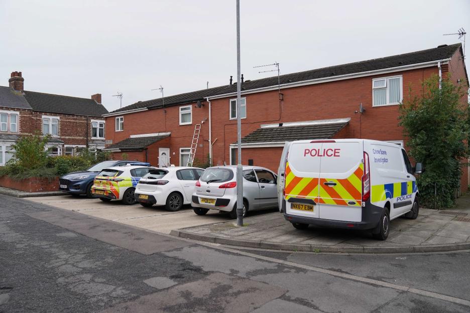 Police vehicles parked outside a house.