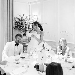 Black and white photo of David and Victoria Beckham at a dinner party.