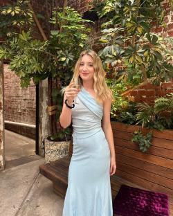Woman in light blue dress holding a champagne flute.