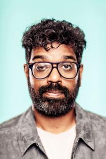 Portrait of Romesh Ranganathan winking.