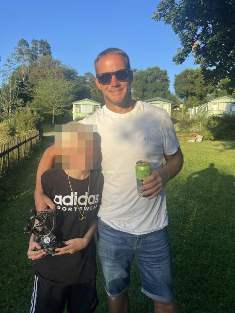 Photo of a man and a child holding a trophy.