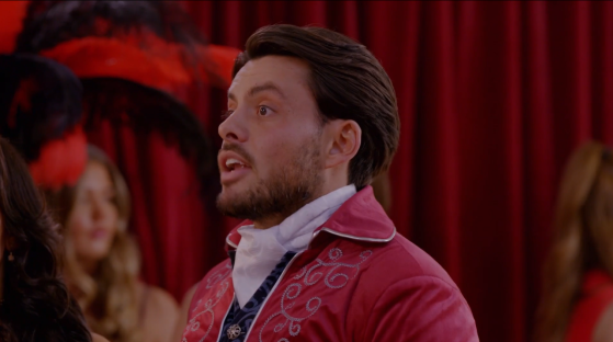 A man in a red jacket speaks emotionally.