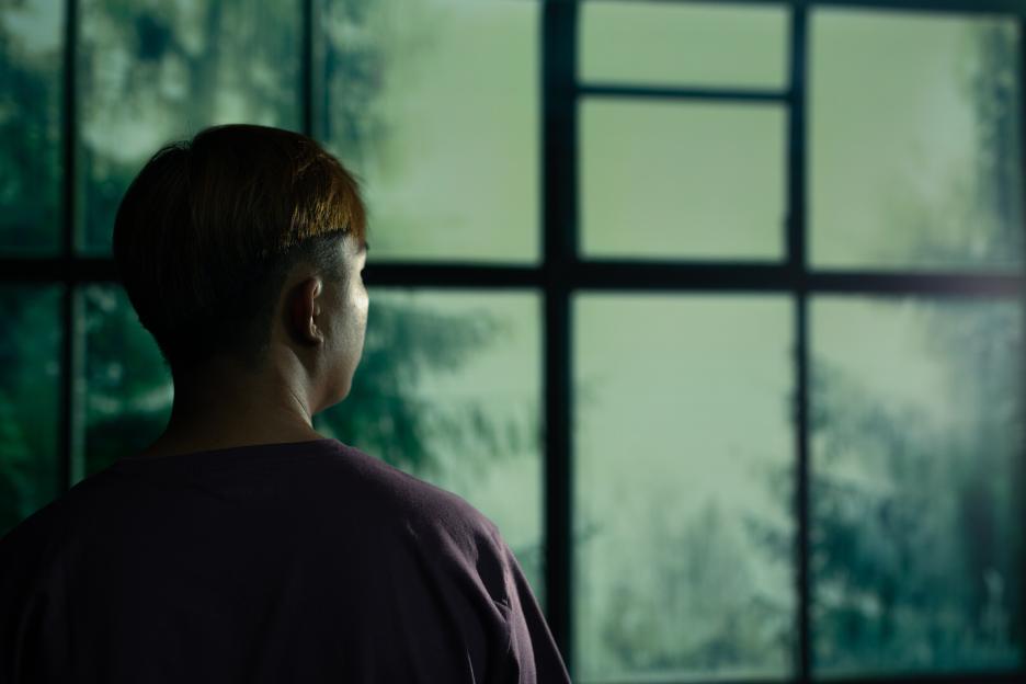 Man from behind looking out a window.