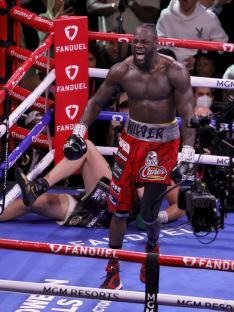 Deontay Wilder reacting after knocking down Tyson Fury in a boxing match.