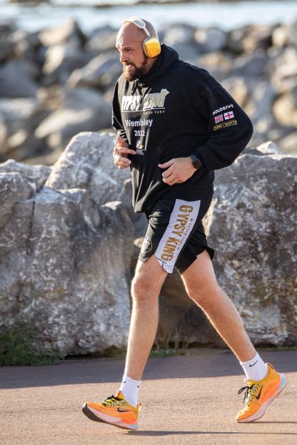 Tyson Fury jogging along a promenade.