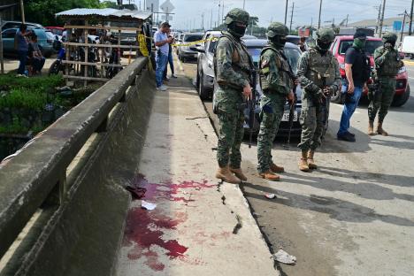 Military officers stand near bloodstains at a crime scene.
