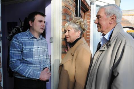 Still image from Coronation Street episode 7602, showing John, Alan, and Dorothy at a doorway.