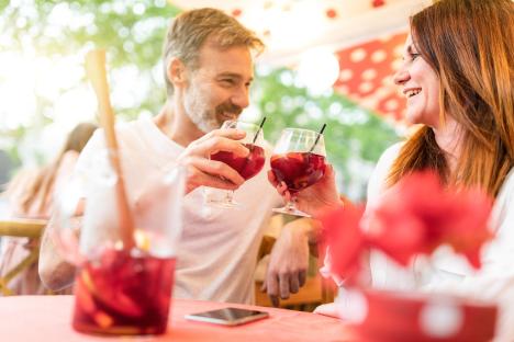 Couple toasting with drinks at a bar.