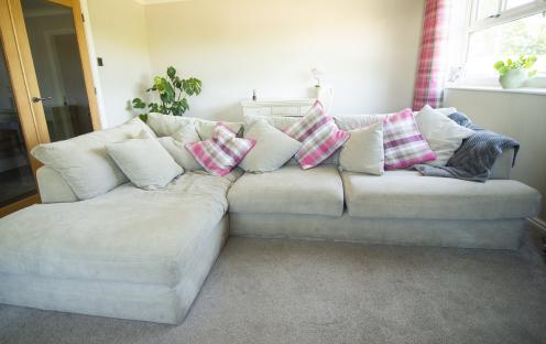 A light grey sectional sofa with pink and grey plaid throw pillows.