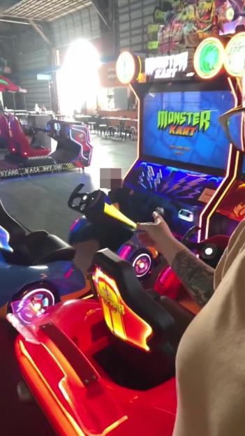 Person playing Monster Kart arcade game.