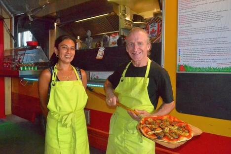 Two pizza makers holding a pizza.