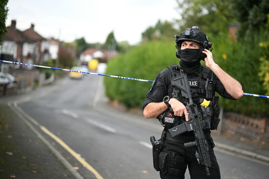 An armed police officer stands by a cordon on White House Avenue following an attack at a synagogue.