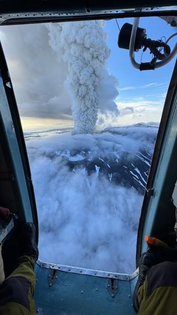 Aerial view of a volcano erupting, seen from inside an aircraft.