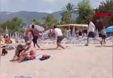 A beach fight breaks out between several people.