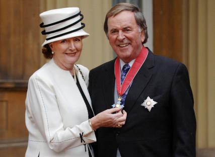 a man and woman are posing for a picture and the woman is holding a medal around her neck