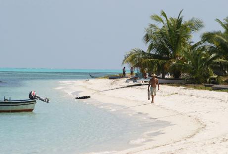 Man walking on a Bangaram Island beach carrying a long object.