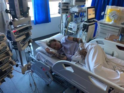 Woman sleeping in a hospital bed with medical equipment nearby.