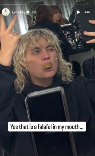 Person holding up peace sign while eating a falafel.