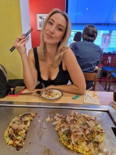 Woman eating okonomiyaki at a restaurant.