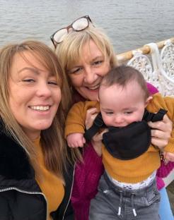 Photo of two women and a baby near water.
