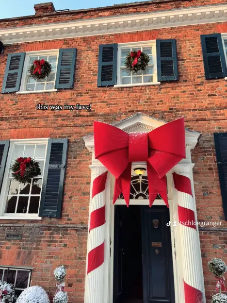 Brick house decorated for Christmas with a large red bow and wreaths.