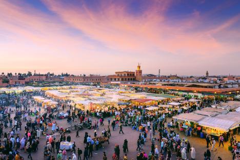Djemaa el-Fna square in Marrakech at dusk, crowded with people and market stalls.