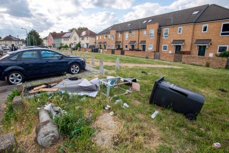 Litter and abandoned furniture on a grassy area in front of residential buildings.