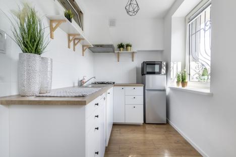 Modern white kitchen with wood countertops and light wood floors.