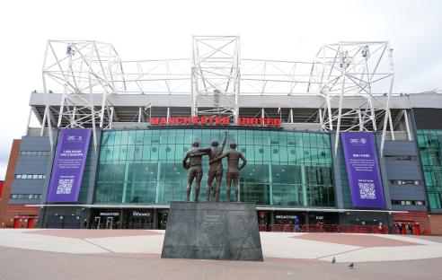 Exterior view of Old Trafford, home of Manchester United, featuring the United Trinity statue.