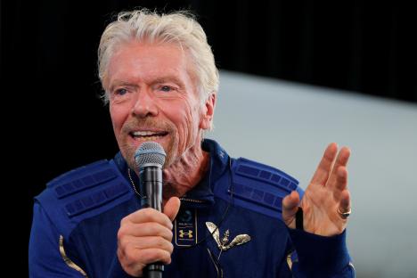 Richard Branson speaking at a news conference, wearing his astronaut wings.