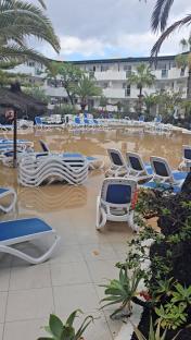 Flooded pool area with submerged lounge chairs at an apartment complex.