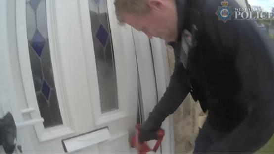 Police officer forcing entry during a County Lines drugs raid.