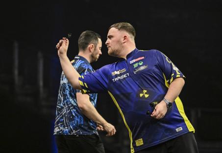 Luke Littler throwing a dart during a darts match.