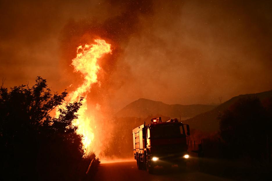 Firetruck driving past a wildfire.